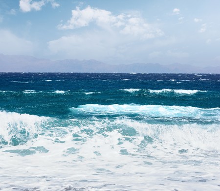 Blue sea with waves and sky with cloudsの写真素材