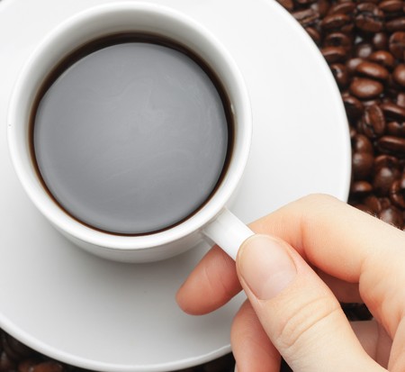 Cup with coffee and hand with coffee beans backgroundの写真素材