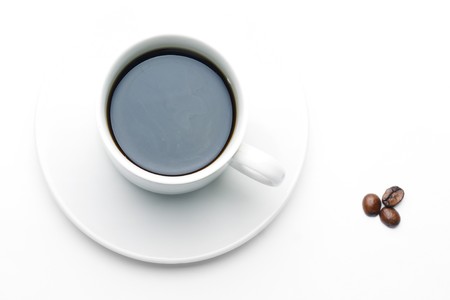 Vanishing cup of coffee on white plate and couple of beansの写真素材