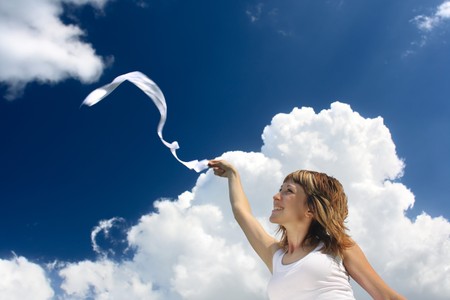 Young smiling woman in white with ribbon over cloudy backgroundの写真素材