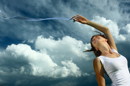 Young woman in white with ribbon over cloudy backgroundの写真素材