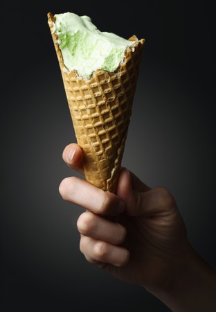 Icecream cone in hand over black backgroundの写真素材