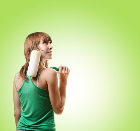 Young woman with roller brush over green backgroundの写真素材
