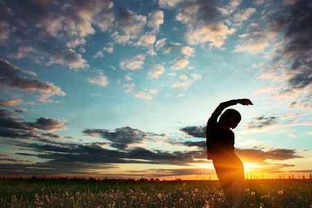 Young woman standing on meadow with herbs under sunset lightsの写真素材