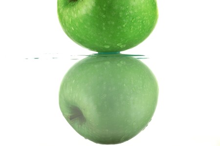 Green apple on white background and reflectionの写真素材