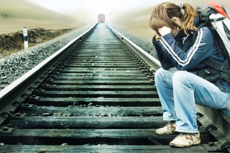 Young woman sitting on railway with comming trainの写真素材
