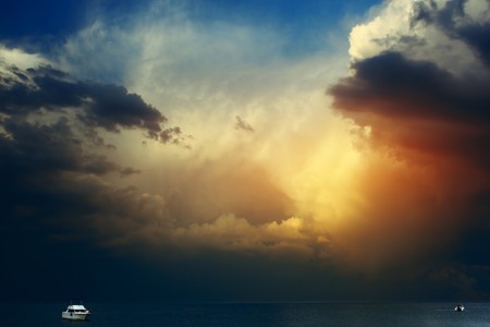 White yacht on sea surface and storm cloudsの写真素材