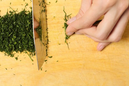 Cutting a dill on wood tableの写真素材