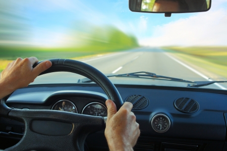 Driver in car holding steering wheel. Blurred road and skyの写真素材
