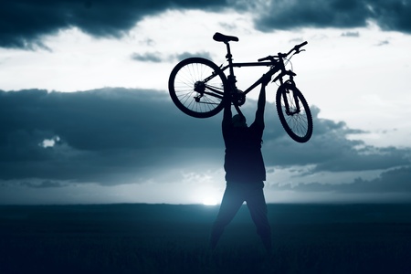 Man with bicycle lifted above himの写真素材