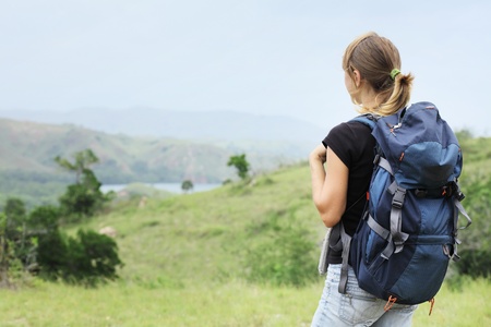 Young woman with backpack walking through a wild territory 