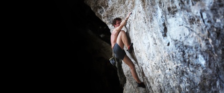 Young semi naked man climbing on a rock without belayの写真素材