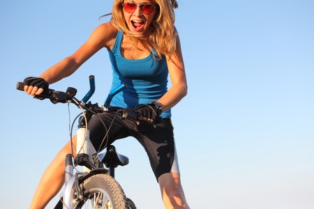 Young woman holding handlebar of a bicycle and shoutingの写真素材