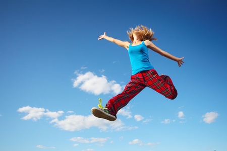 Young happy woman jumping on blue sky background