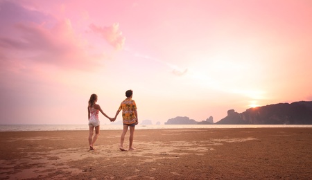 Young couple walking on a sandy coastの写真素材