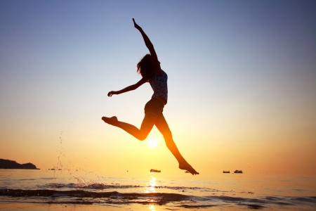 Young woman jumping in a water on a beachの写真素材