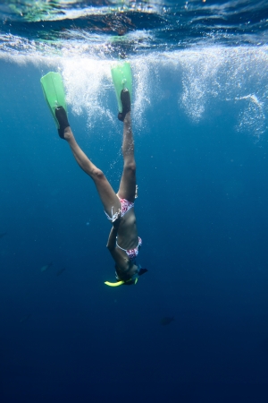 Young woman diving on a breath hold and finning in blue transparent seaの写真素材