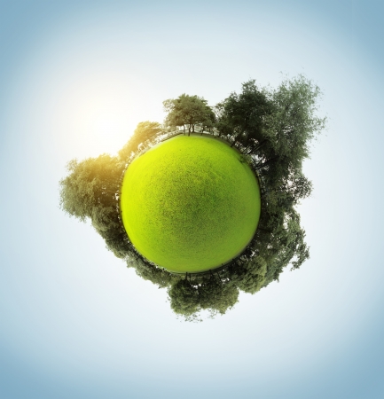 Green little planet with trees meadow and clear sky with sunの写真素材