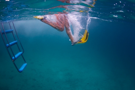 Underwater shoot of a person jumping in tropical sea with yellow fins