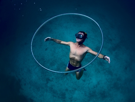 Young freediver making huge ring bubbles underwater and gliding near itの写真素材