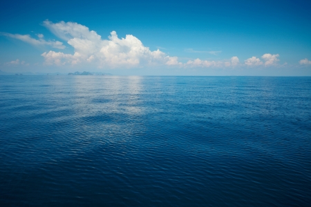 Tropical rippled and calm sea with far islands on the horizon and white fluffy clouds Tropical rippled and calm sea with far islands on the horizon and white fluffy clouds