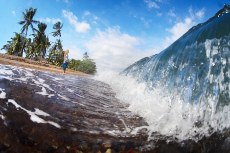 Young woman watching barrel waves on a tropical beach. Philippinesの写真素材