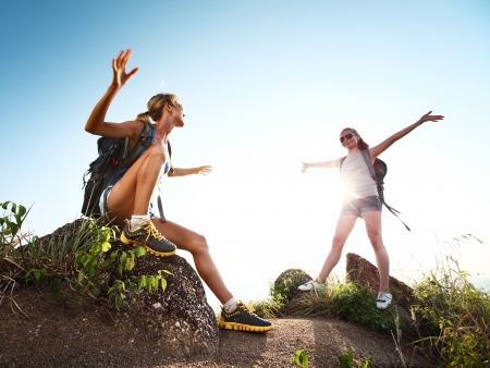 Two hikers with backpacks and with raised hands on top of a hillの写真素材