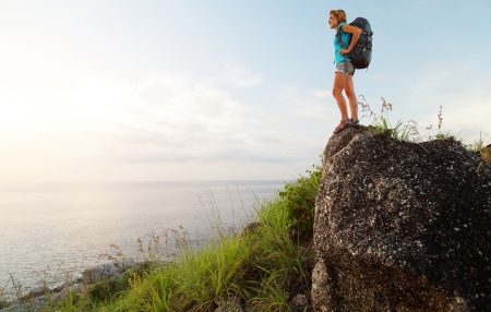 Hiker with backpack enjoying sea view from top of the hillの写真素材