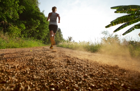 Young lady running on a rural roadの写真素材