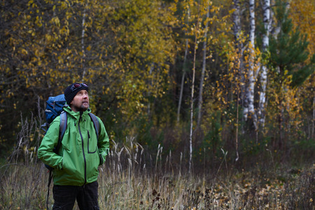 Portrait of the mature backpacker in an autumn forest
