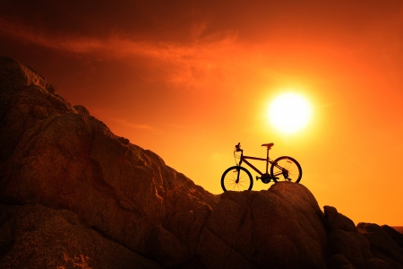 Bicycle standing on a rocks at sunsetの写真素材