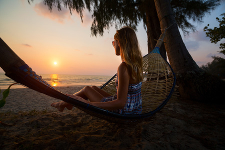 Young lady relaxing in the hammock on a beach at sunsetの写真素材