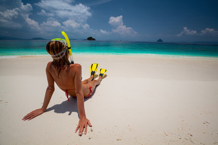 Young lady relaxing on the tropical sandy beach with snorkeling gearの写真素材