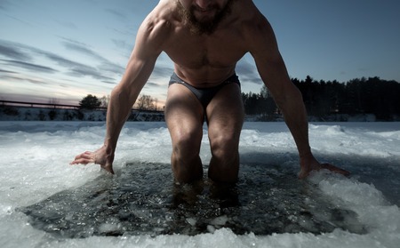 Young man having recreational swim in the ice holeの写真素材