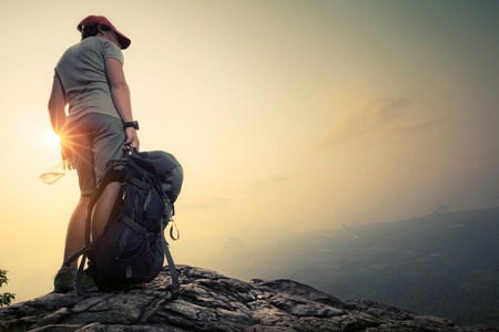 Hiker standing on top of the mountain with backpack