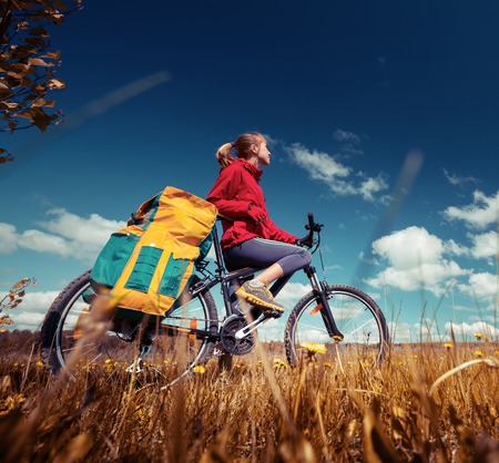 Hiker standing with loaded bicycle in the fieldの写真素材