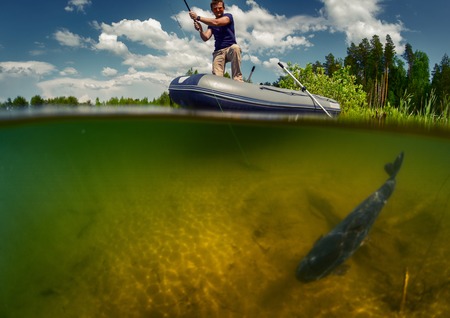 Split shot of the fisherman with rod in the boat and underwater view of the fish near a bottomの写真素材