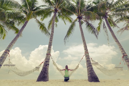 Lady relaxing in the hammock set in the garden with palm treesの写真素材
