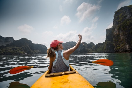 Woman exploring calm tropical bay with limestone mountains by kayak. Ha Long Bay, Vietnamの写真素材