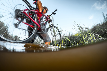 Man crossing the river with bicycleの写真素材