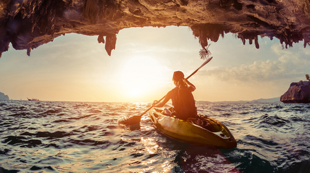 Lady paddling the kayak in the rough sea at sunset.の写真素材