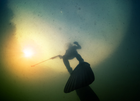 Underwater shot of the hunter with speargun in a lake with dirty waterの写真素材