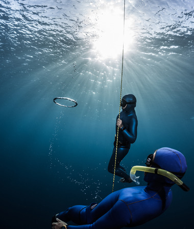 Couple of free divers having fun underwater, making ring bubblesの写真素材