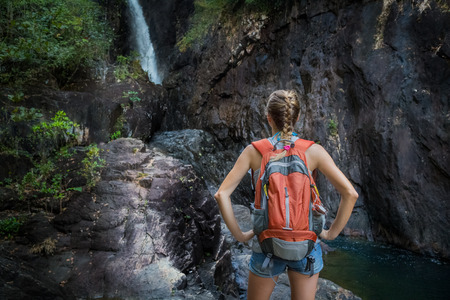 Lady hiker standing on the rock and enjoying view of the waterfallの写真素材