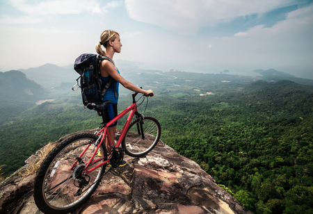 Young lady with Bicycle standing on mountainの写真素材