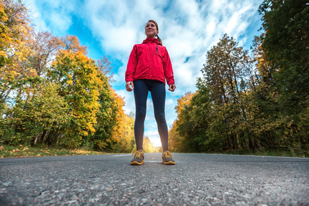 Lady in a track suit standing on the road with trees