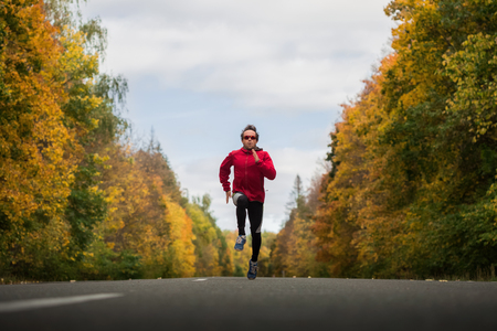 Young athlete running on the autumn roadの写真素材