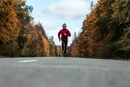 Young athlete running on the autumn roadの写真素材