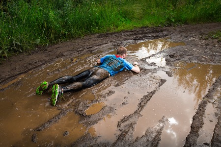 Athlete fall down to the dirty puddle in the rural roadの写真素材