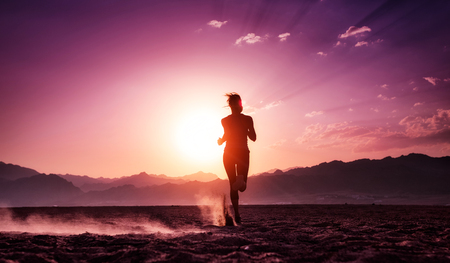 Lady running in the desert at sunsetの写真素材